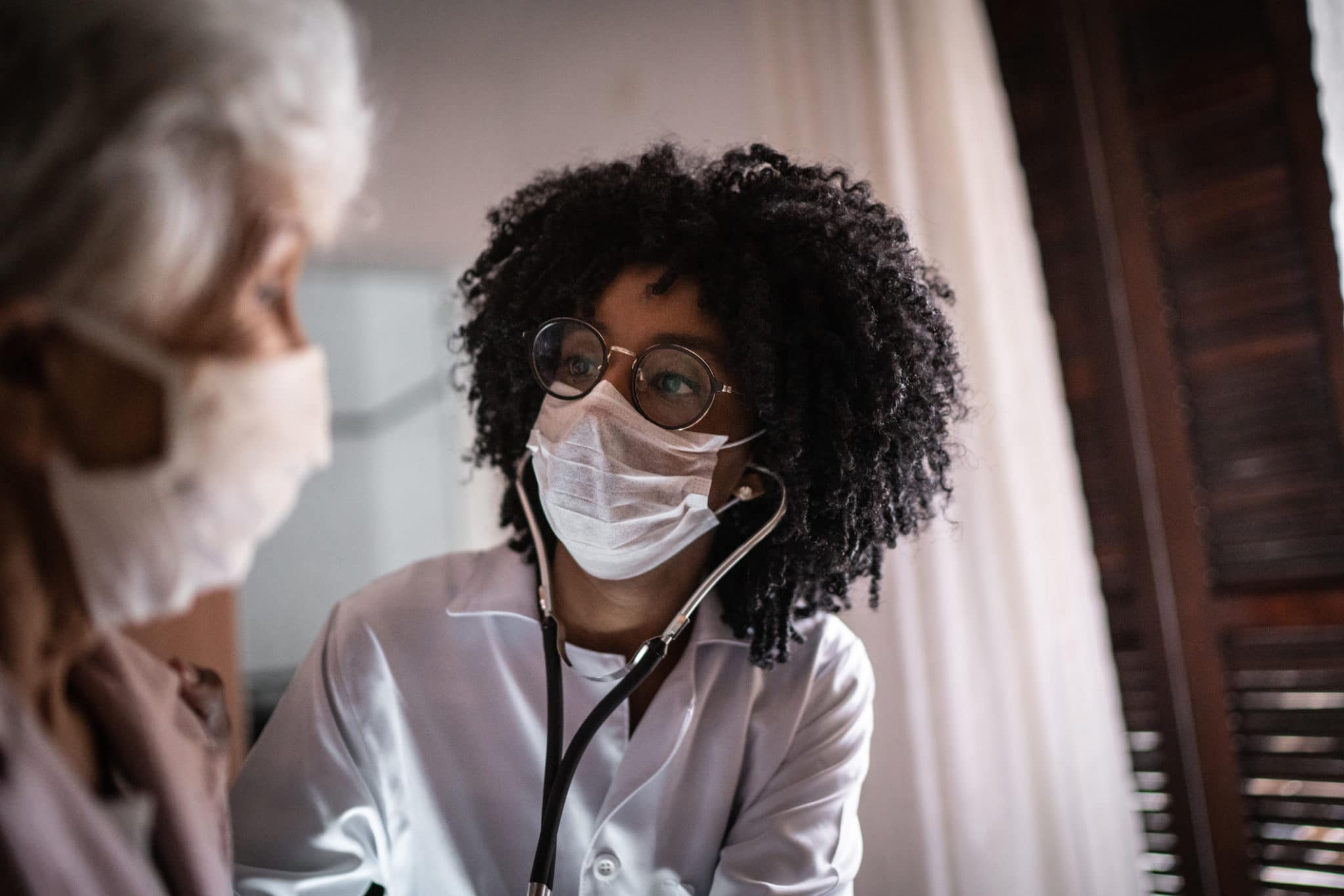 Doctor wears mask and speaks with a masked patient,
