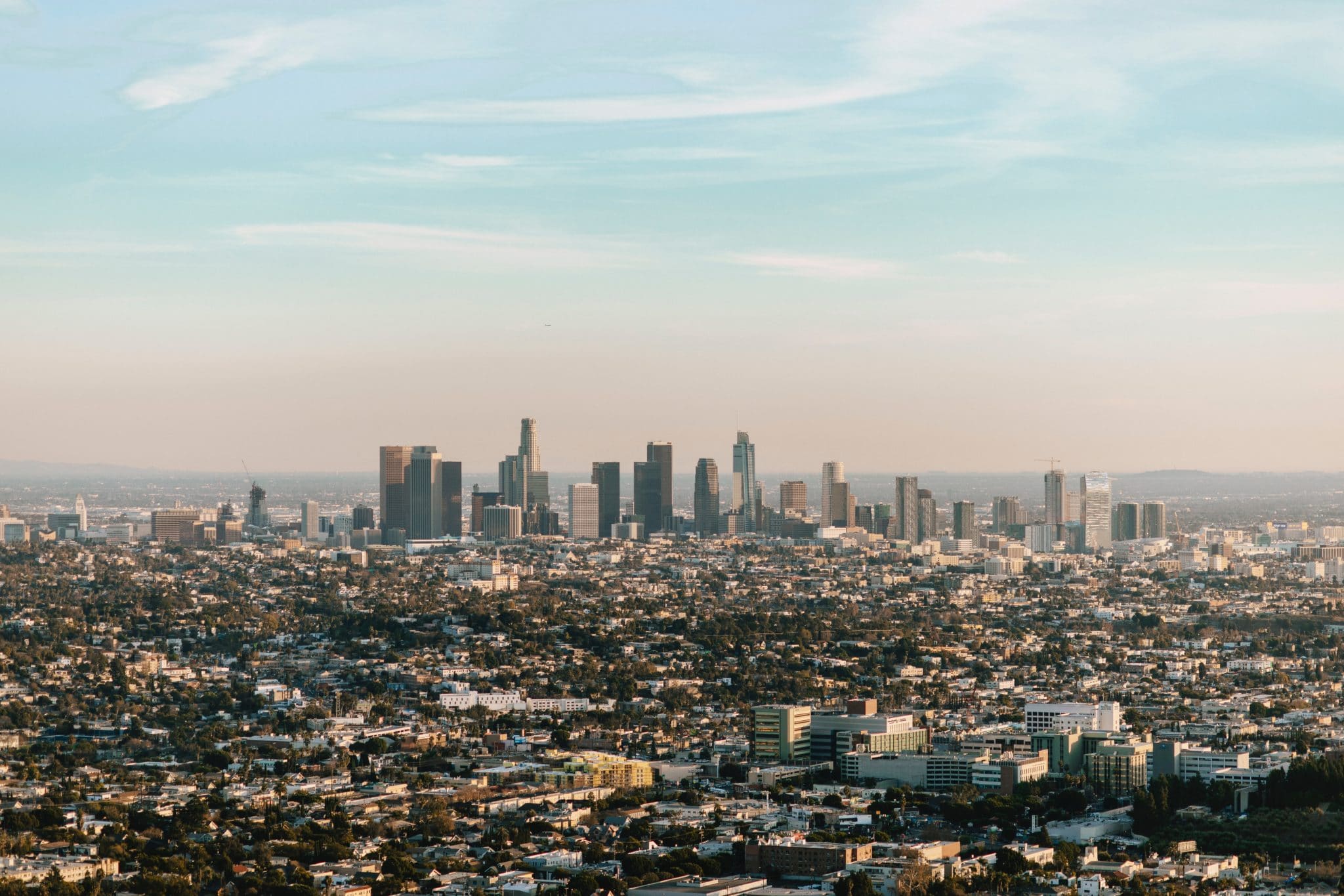 Photo of the Los Angeles skyline with a pale blue and hazy pink sky