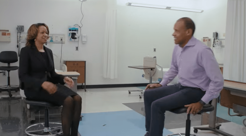 Dawn M. Aycock, Ph.D. and Micheal Sneed are seated in a medical exam room having a conversation