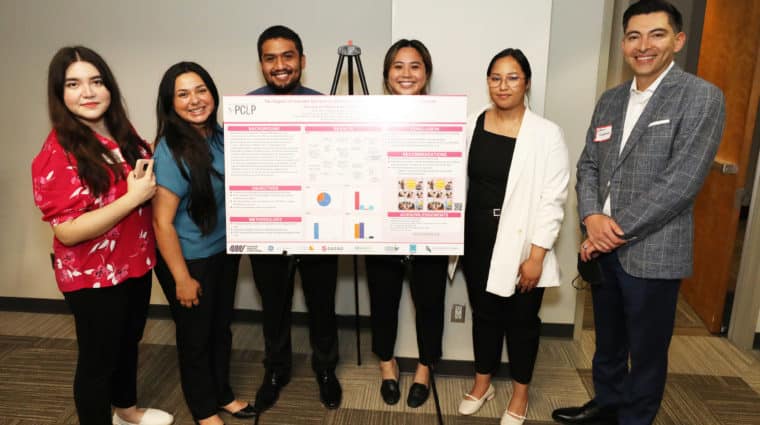 Five students stand around an easel showcasing a poster of one of their research projects. NMF Board Member Dr. Efrain Talamantes stands with them to the right.