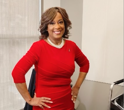 Dr. Sandra Nichols posing for a photo in a red dress and a white necklace