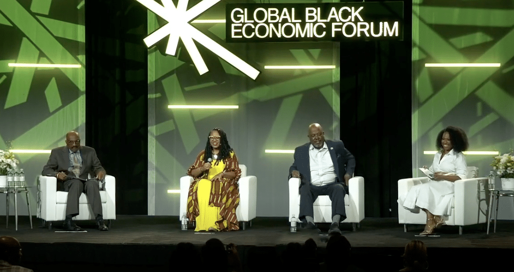 Photo of four people on a stage with a backdrop reading Global Black Economic Forum