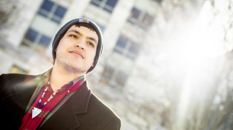 Photo of Victor Lopez-Carmen wearing a gray had, red shirt, and an olive green jacket