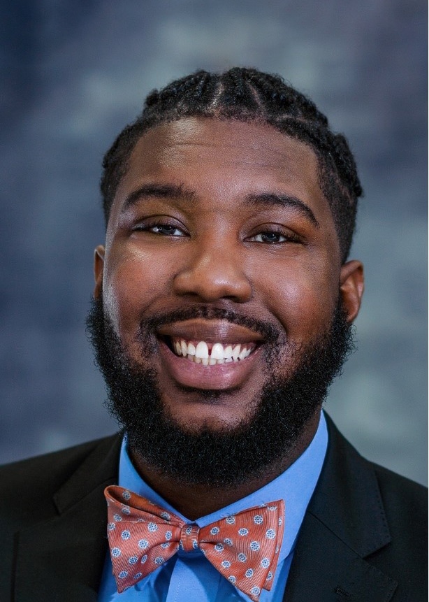 Headshot of Caylon Pettis wearing a black jacket, blue shirt and pink bow tie.