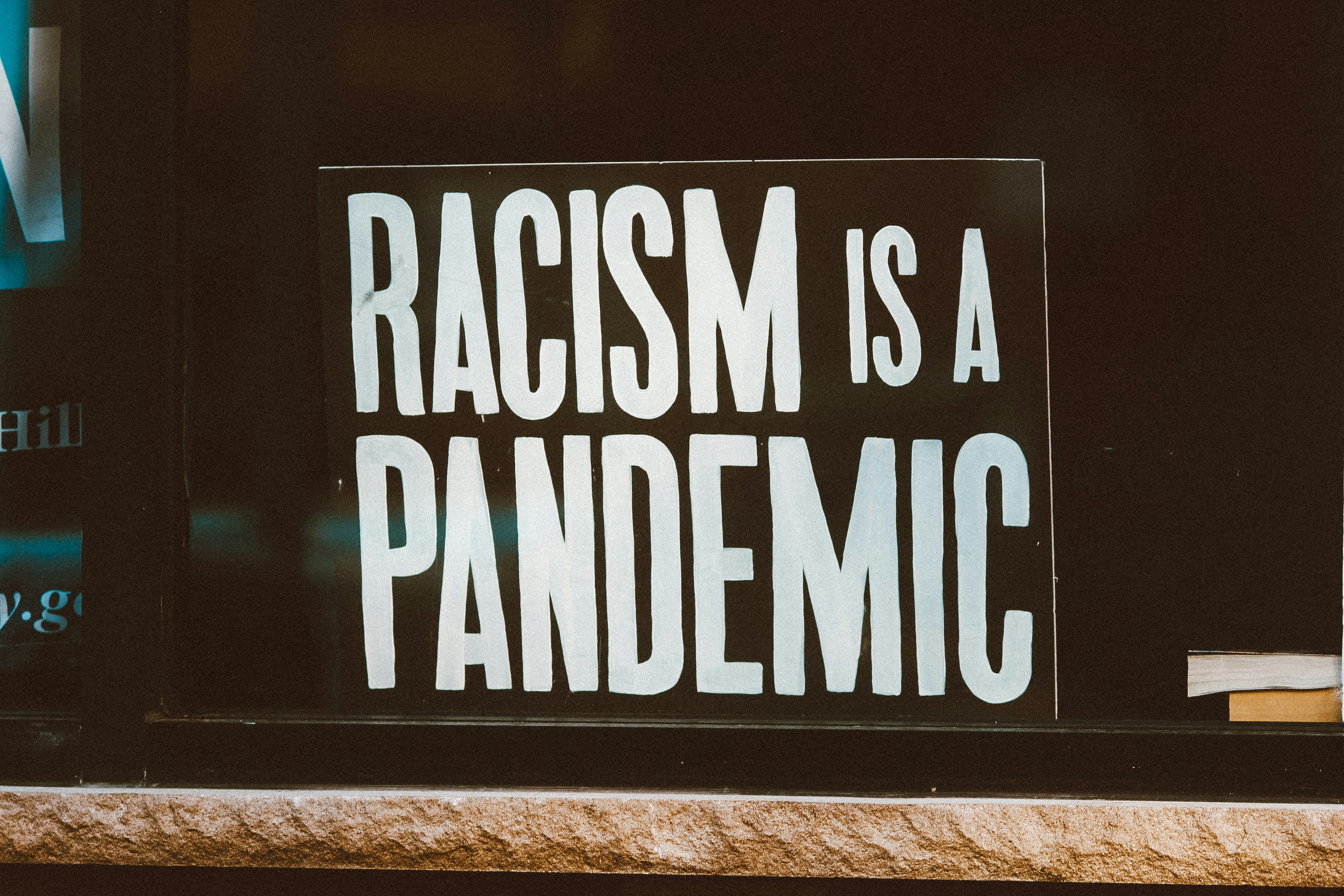 Black sign with white letters reading: Racism is a Pandemic