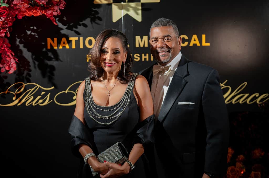 Photo of Dr. Veronica Mallett and Kevin Briscoe in front of a black banner reading National Medical Fellowships