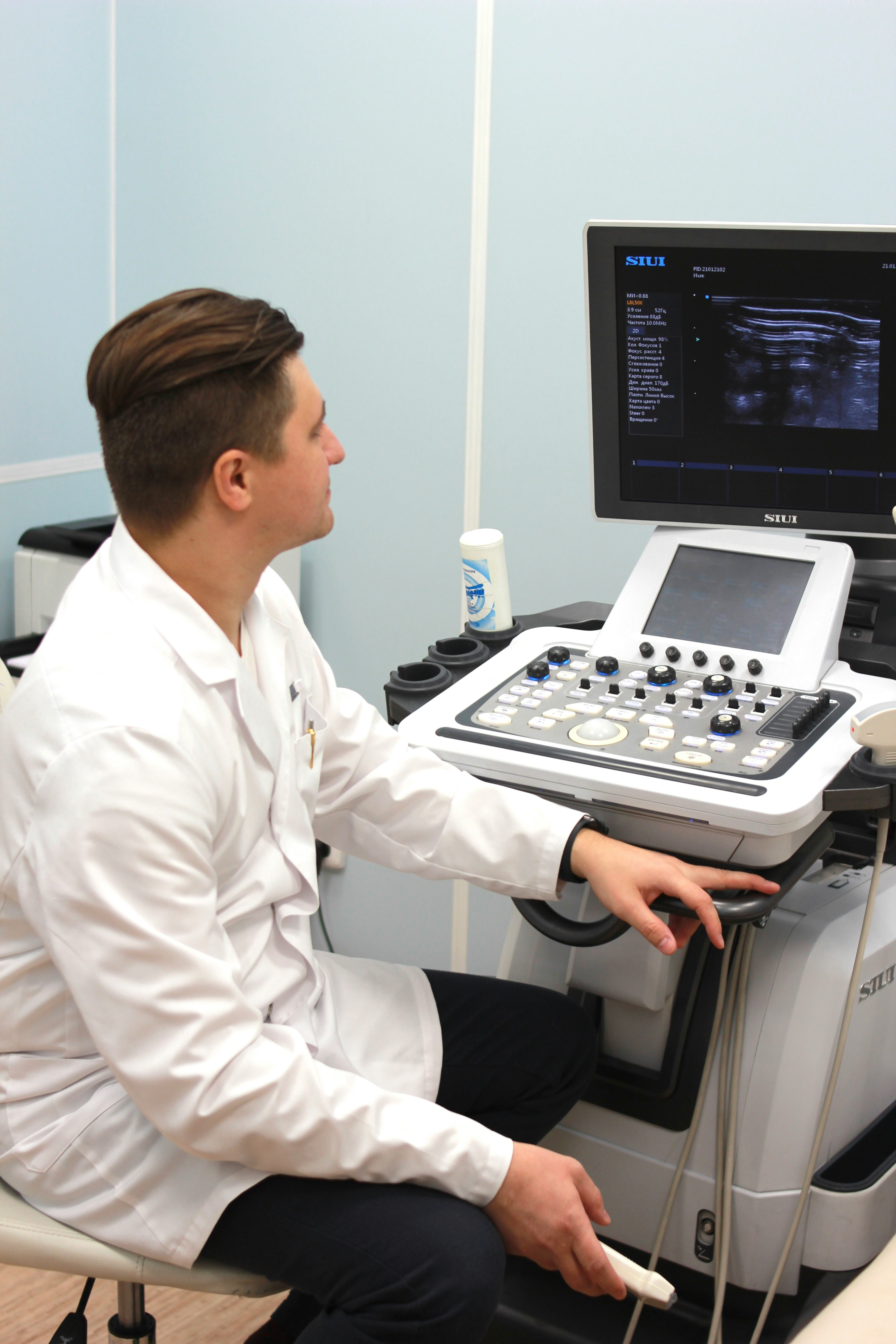 Photo of a doctor in a white coat looking at an ultrasound screen on a computer