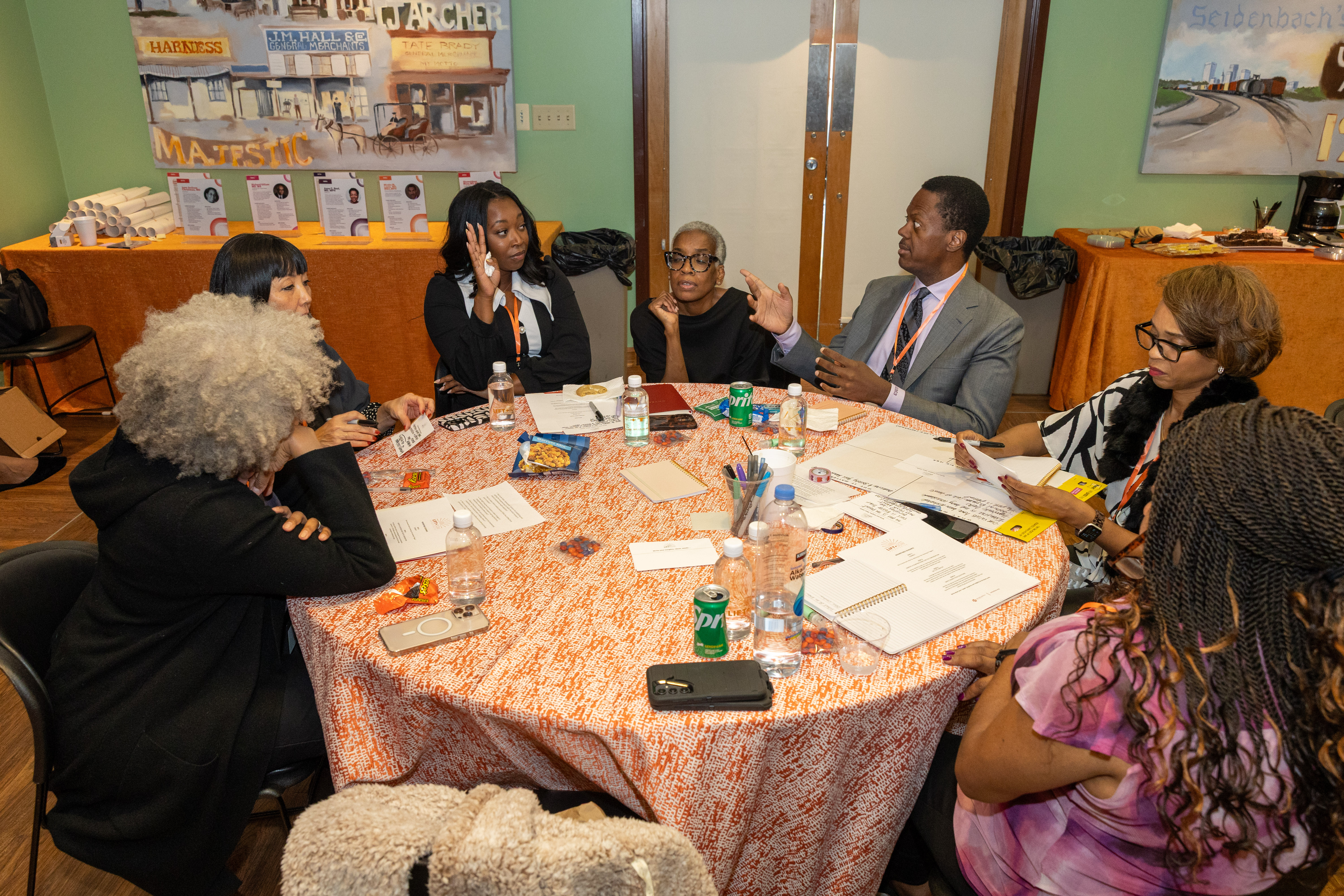 Photo of six roundtable participants seated around a round table, conversing