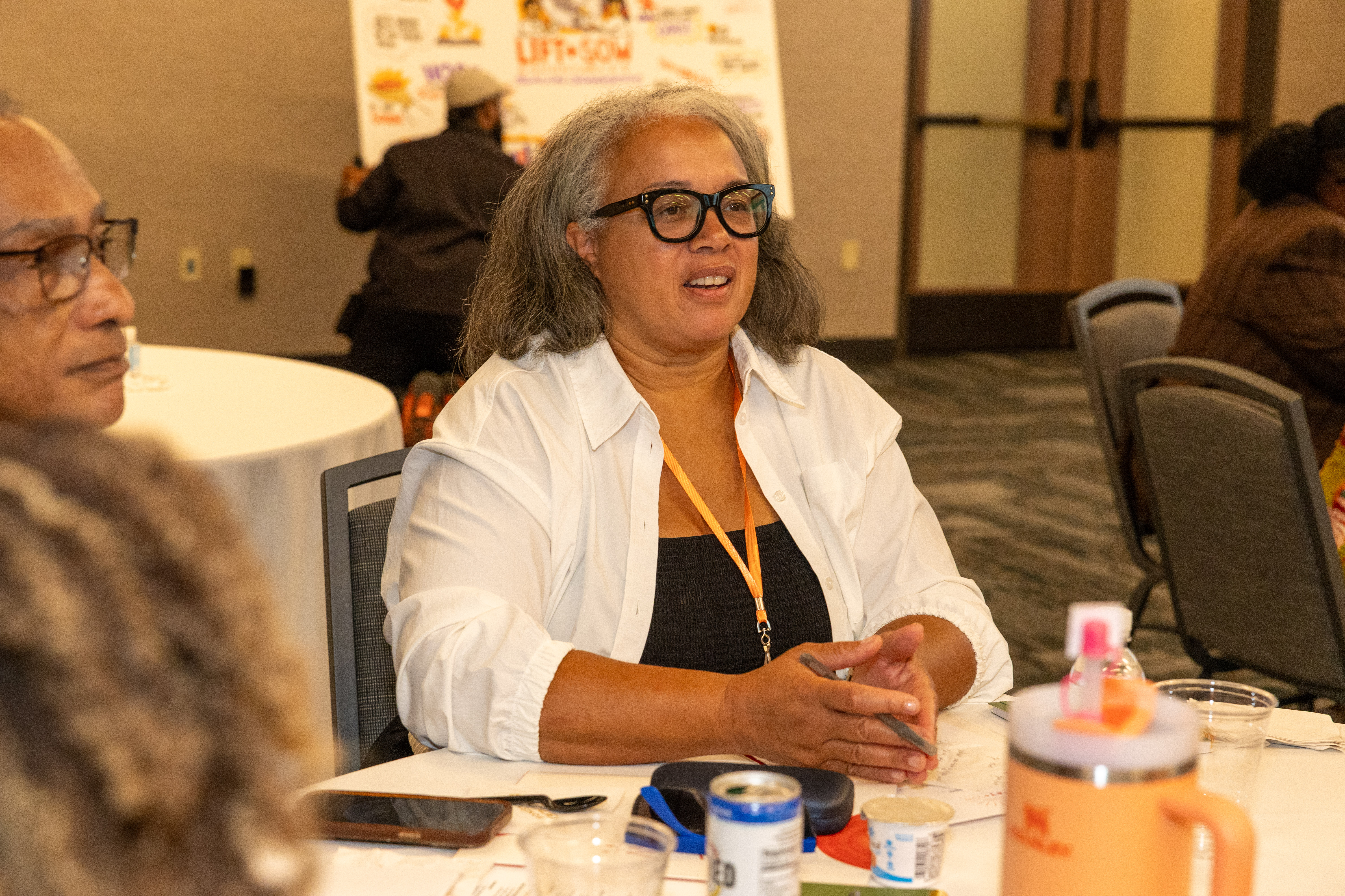 A WOMAN IS REACTING TO A QUESTION. SHE IS WEARING A BLACK AND WHITE TOP AND DARK GLASSES