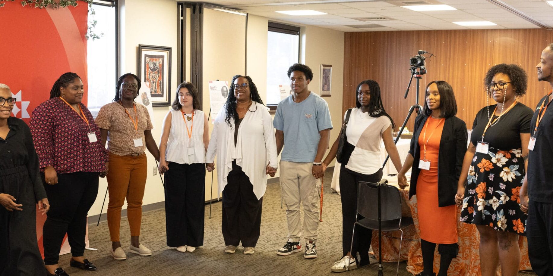 A Group of roundtable participants are holding hands in a conference room