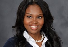 Headshot of NMF scholar Shanice Cox, wearing a black jacket, white blouse, and pearls